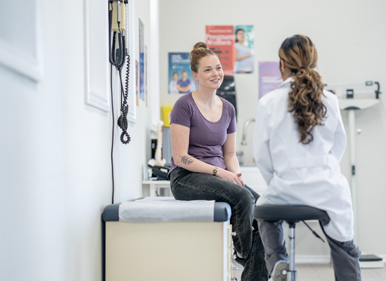 A young woman sitting in a doctor's office opposite her doctor