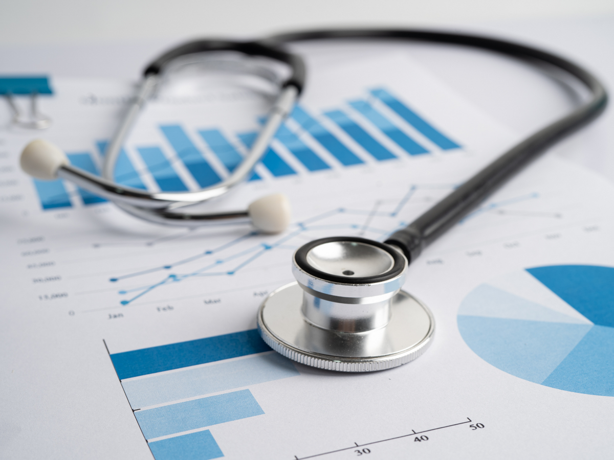 A stethoscope on top of a page showing a range of blue graphs