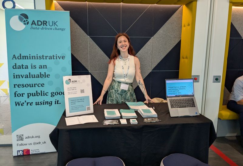 ADR UK stand at an event with a team member smiling behind the table. 