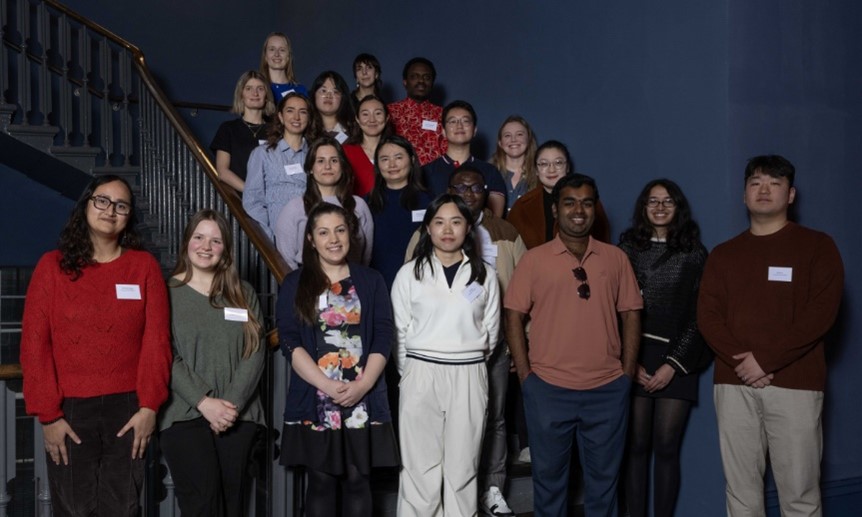 A group of PhD students gathered on a set of stairs, facing the camera